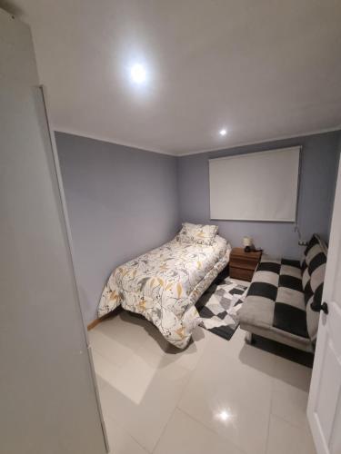 a small bedroom with a bed and a chair at Cabaña in Ancud