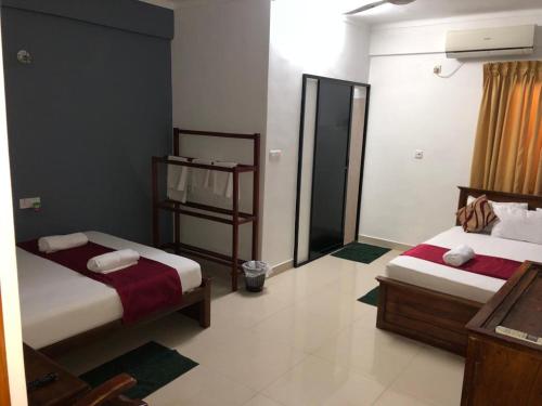 a hotel room with two beds and a bathroom at Yal's Town Inn in Jaffna