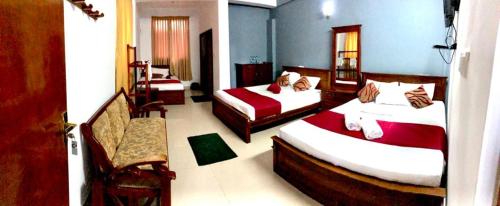 a hotel room with two beds and a chair at Yal's Town Inn in Jaffna