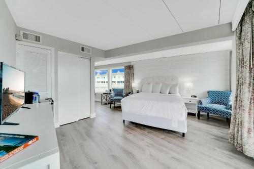 a bedroom with a white bed and blue chairs at Montreal Beach Resort in Cape May