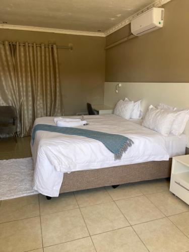 a large bed with white sheets and pillows at LEGENDS EXECUTIVE LODGE in Choma