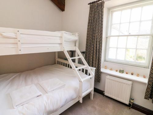 a white bunk bed in a room with a window at Piggy Bank Cottage in Sedbergh