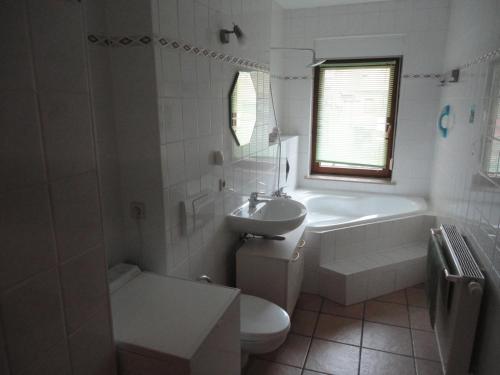 a white bathroom with a tub and a toilet and a sink at Gästewohnungen Hennig in Markkleeberg