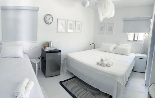 a white bedroom with two beds and a clock at Casa rosada beach front in Mano Juan