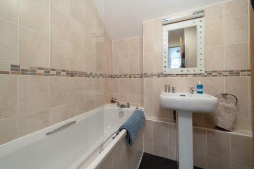 y baño con lavabo, bañera y espejo. en Heron Cottage at Robin Hill 6 en Bideford