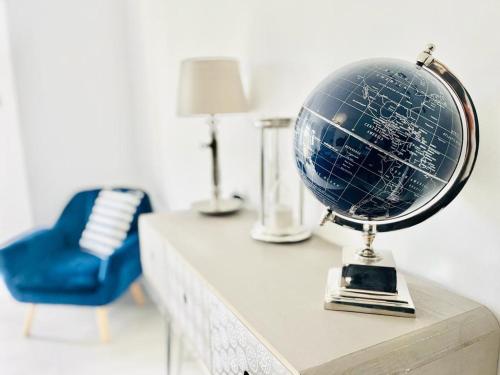 a globe on top of a table with a blue chair at June Disc Long Stay Contractors Seafront Apartment in Portsmouth