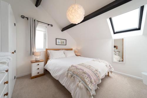 a bedroom with a white bed and a mirror at Puffin Cottage at Robin Hill 6 in Bideford