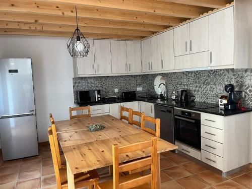 a kitchen with a wooden table and a refrigerator at Quinta do Carvalho Cerquinho in Louriceiras de Baixo