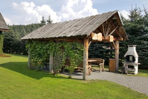 a wooden gazebo with a table and a stove at Chata Sanna in Lesko