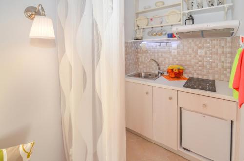 a small kitchen with white cabinets and a sink at Villa Mary Elen in Pollonia