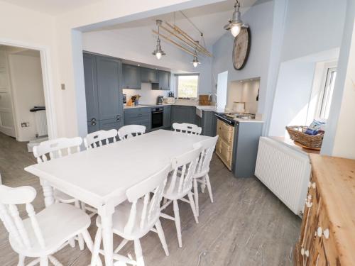 a kitchen and dining room with a white table and chairs at Craig Y Wylan in Amlwch