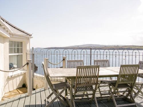 a table and chairs on a deck with a view of the water at Craig Y Wylan in Amlwch