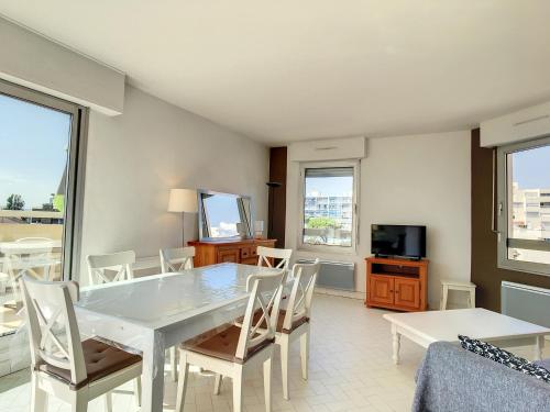 une salle à manger avec une table et des chaises blanches dans l'établissement Location saisonnière - F3 - 8 pers - 1ère ligne - Garage - Animaux acceptés - FR-1-715-3, à Mauguio