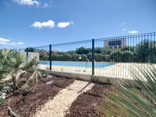 une clôture à côté d'une piscine avec un bâtiment dans l'établissement Appartement T2 avec piscine, tennis, proche port et plage, 4 couchages, Carnon - FR-1-715-33, à Mauguio