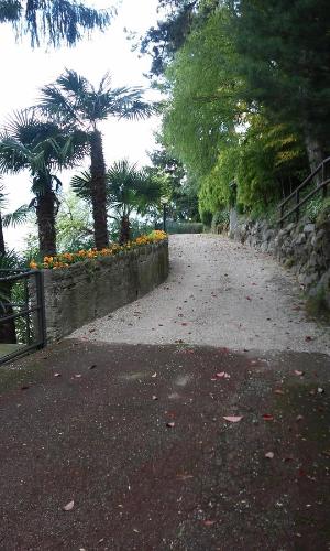 a walkway with a stone wall and flowers at Residenza del Pascià - Appartamento Camphora in Oggebbio