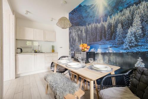 a kitchen with a dining table and a painting on the wall at Giewont View Apartamenty Butikowe & Sauna Grunwaldzka by RentiloPL in Zakopane