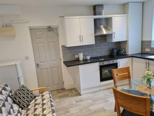 a kitchen with white cabinets and a table in a room at The Lawrence apartment in Bristol