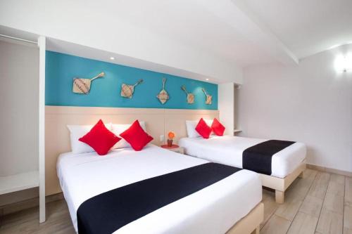 two beds in a hotel room with red and black pillows at Hotel El Andariego in Oaxaca City