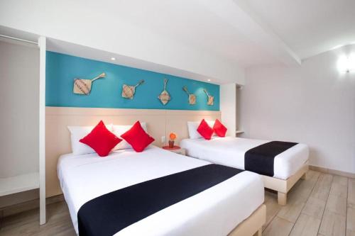 2 camas en una habitación de hotel con almohadas rojas y negras en Hotel El Andariego en Oaxaca de Juárez