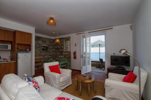 a living room with white furniture and a view of the ocean at Casa do Lado in Povoação