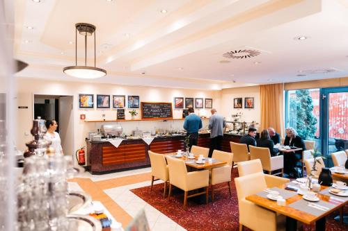a restaurant with people sitting at tables and a bar at City Park Hotel in Frankfurt/Oder