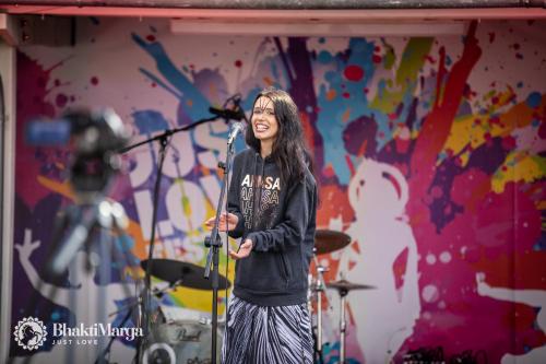 a woman singing into a microphone on a stage at Hindu Monastery - Shree Peetha Nilaya Ashram in Springen