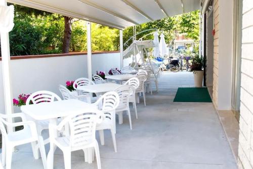 una fila de mesas y sillas blancas en un patio en Hotel Canoa, en Cervia