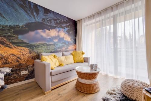 a living room with a couch and a large painting at Giewont View Apartamenty Butikowe & Sauna Grunwaldzka by RentiloPL in Zakopane