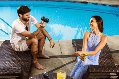 a man taking a picture of a woman sitting next to a pool at Country Club Lima Hotel – The Leading Hotels of the World in Lima