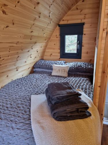 a bed in a room with a wooden wall at Lochview Pods in Harlosh
