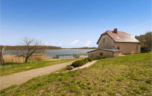 a house on the side of a road next to a lake at 2 Bedroom Amazing Home In Bogaczewo in Bogaczewo