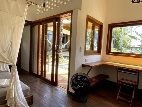 Zimmer mit einem Ventilator und einem Schreibtisch mit Fenstern in der Unterkunft Casa do Jardim in Serra Grande