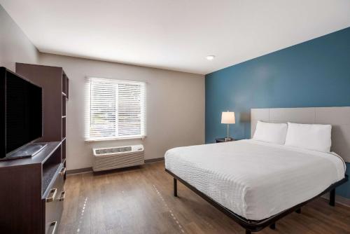 Schlafzimmer mit einem Bett und einem Flachbild-TV in der Unterkunft WoodSpring Suites Orlando North - Maitland in Orlando