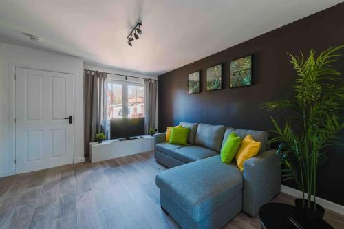 sala de estar con sofá azul y almohadas verdes en ComfySleep ApartHOUSE, en Glasgow