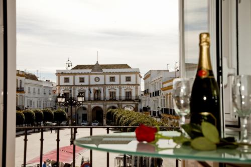 una botella de vino sentada en una mesa frente a un edificio en Apartamentos La Casa de la Alameda, en Medina Sidonia