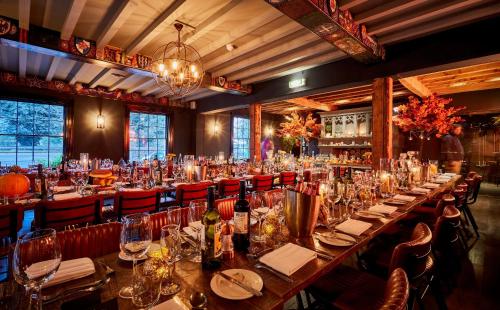 une grande salle à manger avec de longues tables et chaises dans l'établissement The Vicarage, à Holmes Chapel