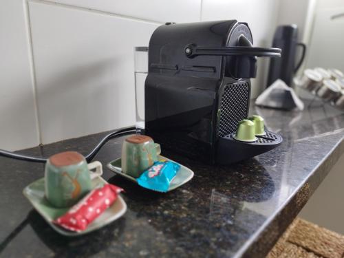 a black counter top with cups and a microwave at Loft charmoso na zona Leste de Teresina in Teresina