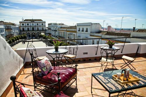un balcón con mesas y sillas en la azotea en Apartamentos La Casa de la Alameda, en Medina Sidonia