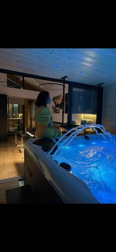 une femme assise dans une piscine dans une pièce dans l'établissement Les suites de Stanislas jacuzzi & spa, à Nancy