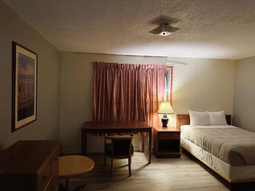 Habitación de hotel con cama, escritorio y ventana en Uptown Motel, en Estevan