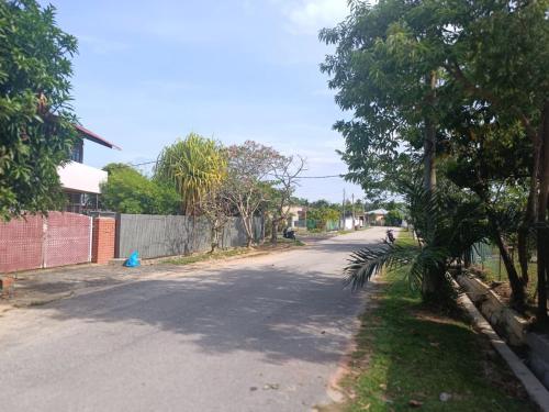 une rue vide avec des arbres sur le côté de la route dans l'établissement BUTIK VILLA, à Port Dickson