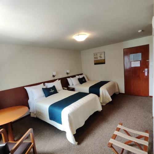 a hotel room with two beds and a table at Hotel Carmel in Lima