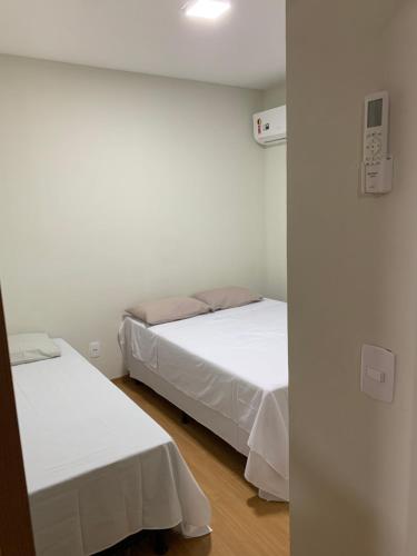 two beds in a room with white walls at Apto ao lado do Caruaru shopping 06 in Caruaru