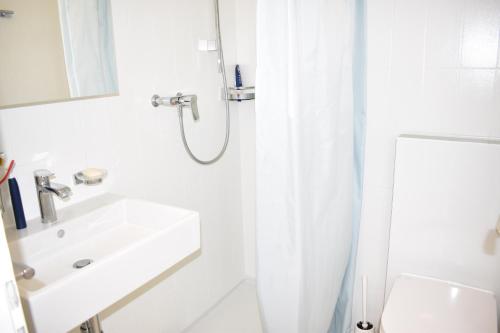 a white bathroom with a sink and a shower at Seegarten A 110 Wy in Lenzerheide