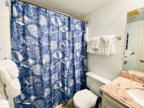 a bathroom with a blue shower curtain and a toilet at SunSwept 505 by ALBVR - Beachfront condo at a great location! in Orange Beach