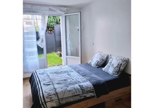 a bed sitting in a bedroom with a window at Superbe appartement avec jardin proche Versailles in Saint-Cyr-lʼÉcole