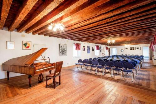 Cette grande chambre dispose d'un piano à queue et de chaises. dans l'établissement Villa Trigatti Udine Galleriano, 