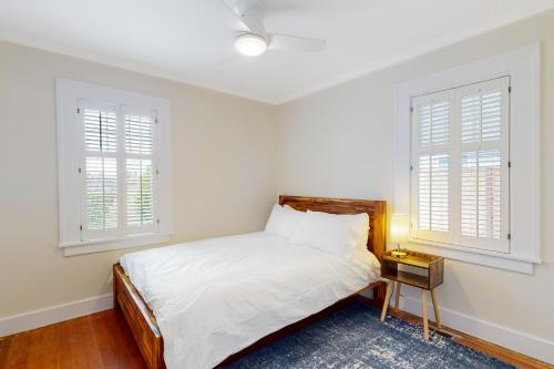 a white bedroom with a bed and two windows at Little City Farms Casita in Seattle