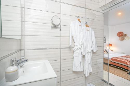 La salle de bains blanche est pourvue d'un lavabo et d'un miroir. dans l'établissement Au Roseau des Indes Appt avec piscine jardin et Fibre, à Les Trois-Îlets