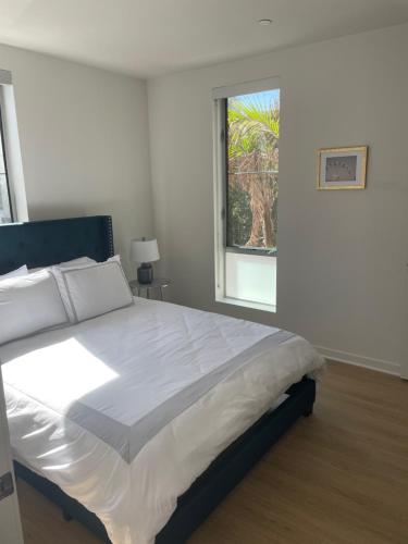 a white bedroom with a large bed and a window at Las Palmas - Modern, Stylish, Spacious, Secure & Tranquil Condo with 2 Master Suite Bedrooms - WLK to SM Pier in Los Angeles